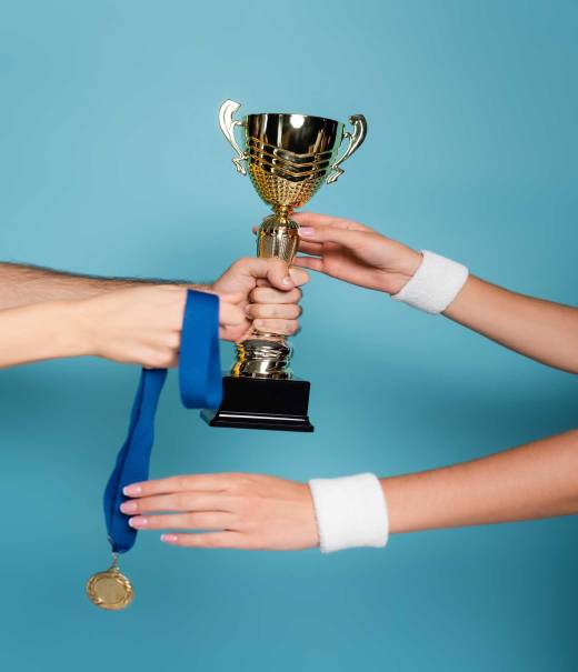 cropped view of man giving golden trophy and medal to female champion on blue